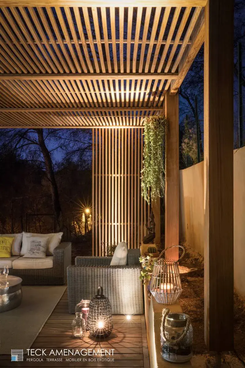 Aménagement extérieur en bois avec pergola et éclairage chaleureux.
