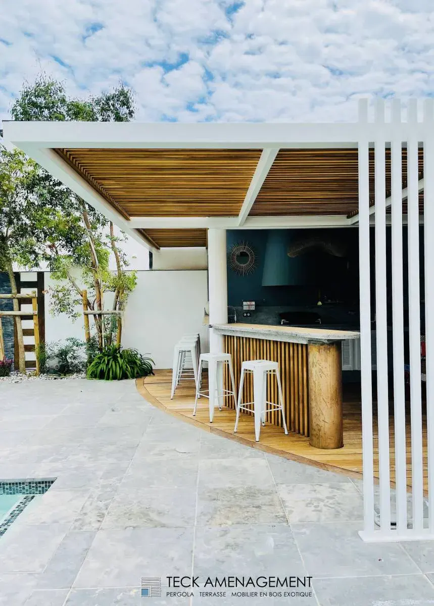 Aménagement extérieur avec bar en bois et mobilier blanc, espace convivial et design.